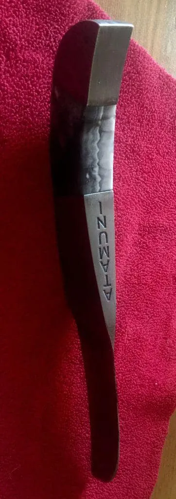 Knife with a dark handle and an engraved metal section lying on red cloth