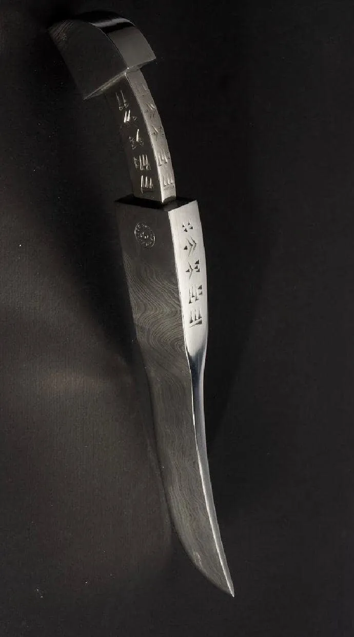 Finished Atamuni knife seen from above, with engraved signs on the handle and blade edge