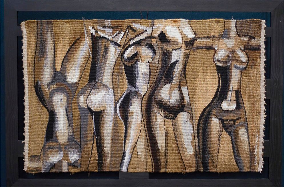 Tapestry “Five women”: five standing nude women cut off at the head, in brown, white and grey on a woven golden background, in a dark frame.