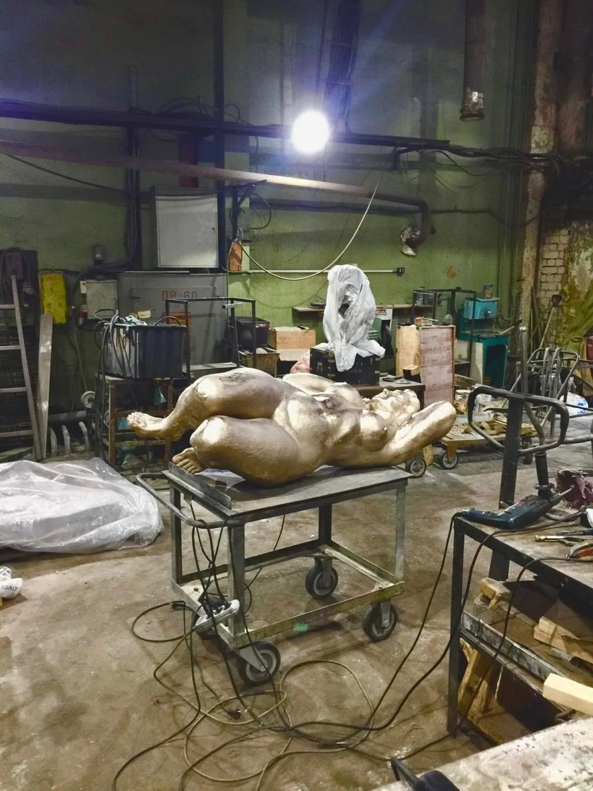 Gilded-looking cast figure lying on a trolley in the foundry