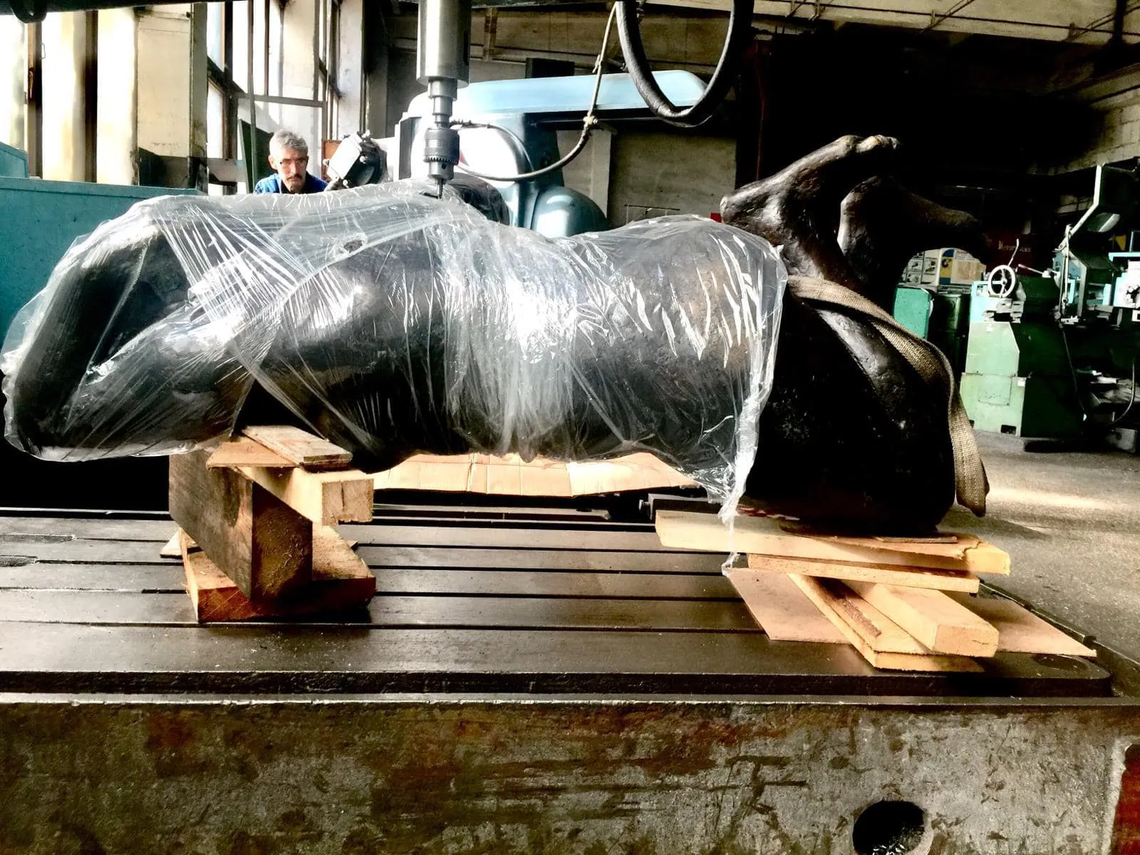 Sculpture wrapped in protective film on the bed of a drilling machine