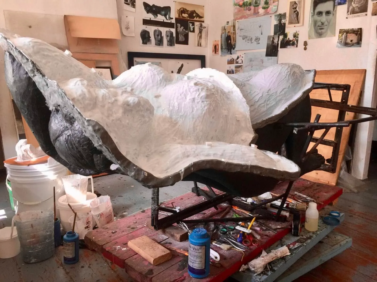 White mould shell lifted open over the sculpture in the studio