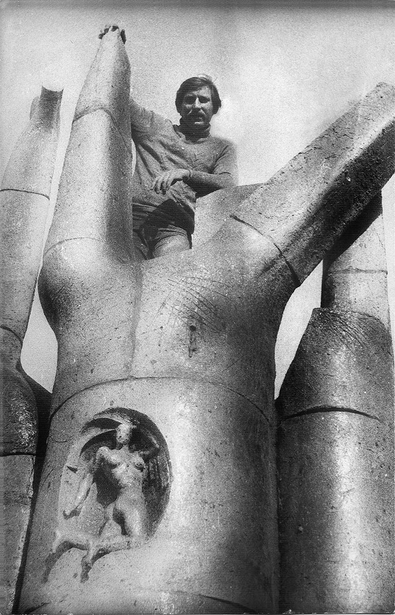 Black-and-white photo of the large chamotte sculpture “Travel to the sky”: tall rounded forms like fingers, with a small figure in a niche and the artist standing on top.