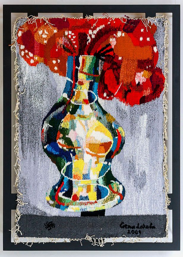 Tapestry “Vase with the flowers - 2”: a vase made of many coloured patches under big red flowers, on a grey background, in a dark frame.